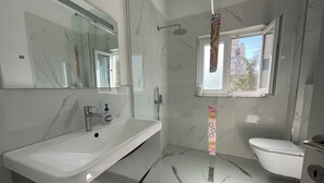 Un bagno moderno con lavabo in marmo, doccia e WC.