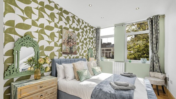 A bedroom with a bed, dresser, and window with curtains.