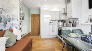 A modern kitchen with white cabinets, a built-in oven, and a dining area with a table set for two.