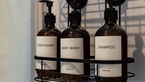 Three bottles of conditioner, body wash, and shampoo on a shelf.