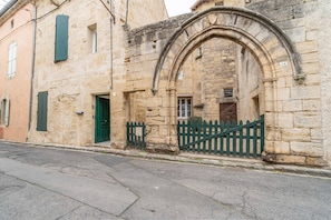 Un bâtiment en pierre avec une porte verte et une enseigne blanche au-dessus.