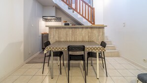 A compact kitchen with a dining area, a staircase, and a view of the outside. - Unique Apartment with Parking and Wi-Fi (Saint-Thibéry)