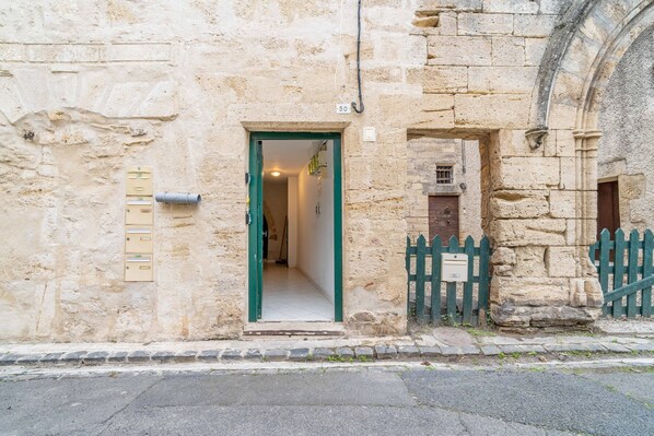 A stone building with a green door, a mailbox, and a small wooden fence.