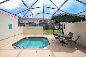 A covered outdoor area with a pool, patio furniture, and a view of residential buildings.