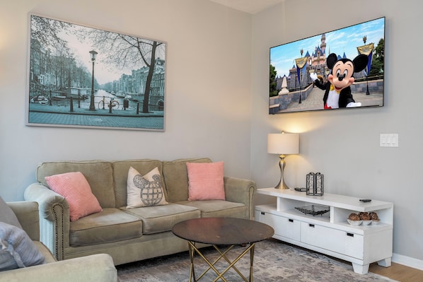 A living room with a sofa, a coffee table, a TV, and a lamp.