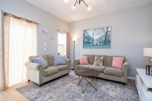 A living room with two sofas, a coffee table, a painting, and a lamp.