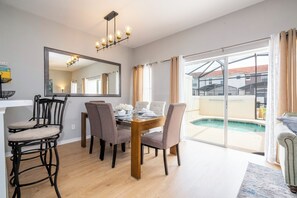Un comedor con una mesa y sillas, un espejo grande y vista a una piscina.