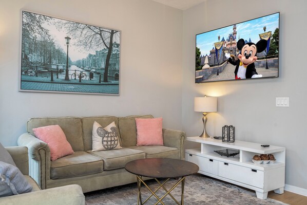 Una sala de estar con sofá, mesa de centro, televisor y lámpara.
