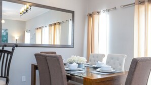A dining area with a wooden table, four chairs, a large mirror, and a chandelier. - 4BR Bella Vida Villa with Pool, BBQ & Themed Rooms near Disney (Kissimmee)