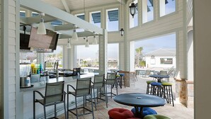 An outdoor patio area with a bar, seating, and a view of the beach.