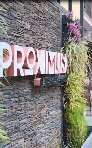 A stone wall with a sign that reads "PROXIMUS."