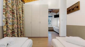 Camera d'albergo con due letti, un armadio, una televisione a parete e un soffitto in legno.