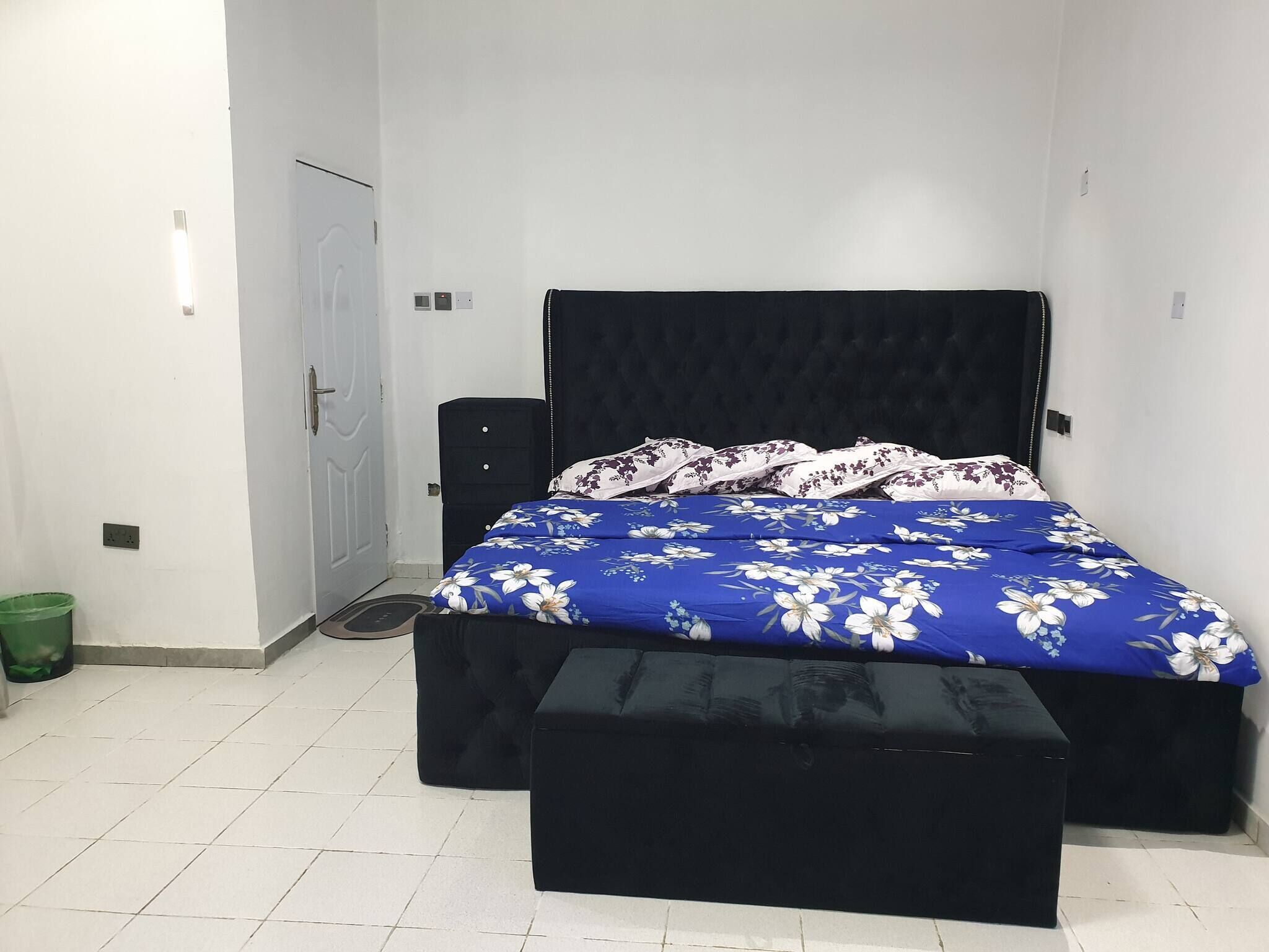 A bedroom with a bed, a bench, a wardrobe, and a door.