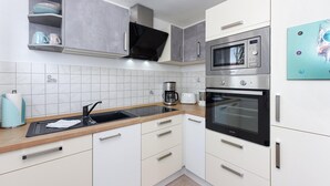 A modern kitchen with a built-in microwave, oven, and coffee maker. - Wohnung nur 300 m vom Strand in Bensersiel (Bensersiel)