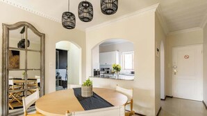 A dining area with a round table, chairs, a mirror, and hanging lights. - Balcony in Trees|1km to  Mandela Sq (Sandton)