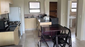 A compact kitchen with a dining area, a built-in oven, and a window above the sink.