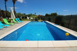 Una piscina rectangular con agua azul cristalina, rodeada por un solárium con baldosas.