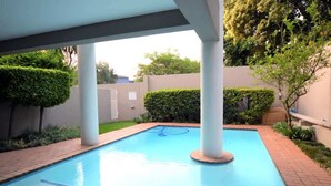 Una piscina con superficie de agua azul cristalina, rodeada por un paseo de ladrillo y columnas blancas.