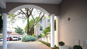 Un pasillo cubierto con piso de ladrillo, columnas blancas y plantas en macetas.