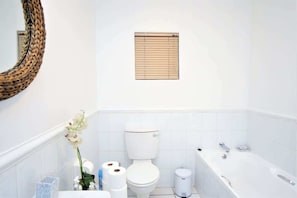 Un bagno con un water, una vasca da bagno e una piccola finestra sopra il water.