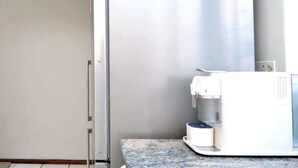 Una cocina con una cafetera en la encimera y un refrigerador al fondo.