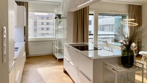 Una cocina moderna con armarios blancos, una isla de vidrio y vistas a la ciudad.