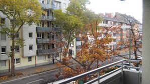 A residential area with multi-story buildings, a street with fallen leaves, and a person walking. - Central apartment with secure private parking in the backyard (Ludwigshafen am Rhein)