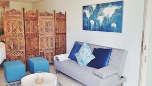 En stue med en grå sofa, blå puder og et verdenskort på væggen.