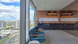 A modern waiting area with a view of the city, a reception desk, and seating. - For You Moema (São Paulo)