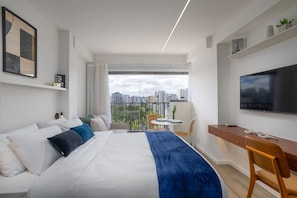 A modern hotel room with a large bed, a desk, a TV, and a balcony with a city view. - For You Moema (São Paulo)