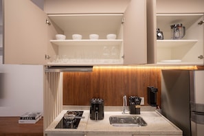 A modern kitchen with a built-in stove, a coffee maker, and a wine glass rack. - For You Moema (São Paulo)