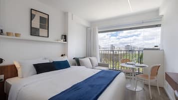 Et moderne hotelværelse med en stor seng, en balkon med spiseplads og udsigt over byen.
