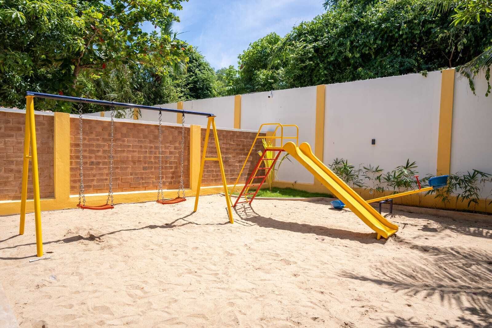 Une aire de jeux avec des balançoires, une échelle et un toboggan.