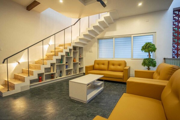 Una sala de estar moderna con una escalera, un sofá, una mesa de centro y una planta en maceta.