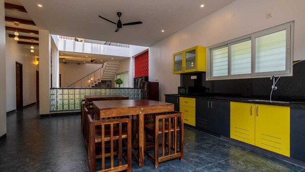 Une cuisine moderne avec des meubles de couleur jaune, une table à manger en bois et un escalier menant à un niveau supérieur.