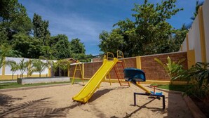 Ein Spielplatz mit einer gelben Rutsche und einem blauen Eimer.