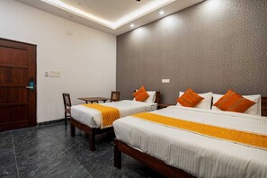 Una habitación de hotel con dos camas, una puerta de madera, una mesita y una silla.