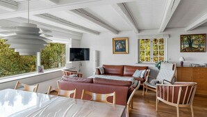 Amplia sala de estar con un ventanal, un sofá, una mesa de comedor y un televisor.