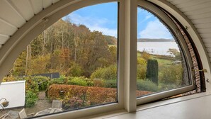 Una habitación con un amplio ventanal de arco que da a un jardín y un lago.