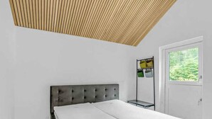 A bedroom with a bed, a window, and a wooden slatted ceiling. - 5 Star Holiday Home in Sunds (Sunds)