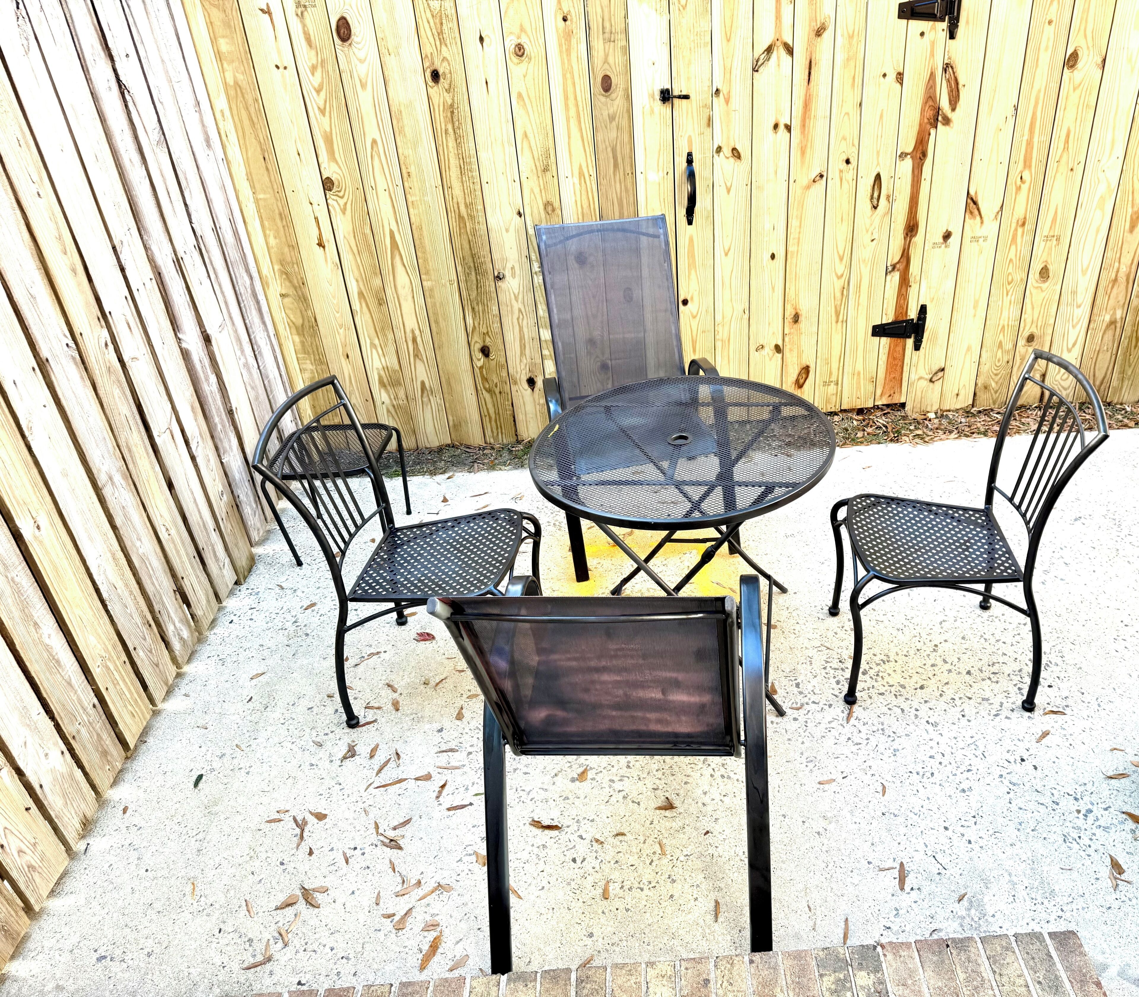 A round metal table with a mesh top, surrounded by four black metal chairs.