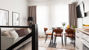 A modern living room with a sofa, a dining table with chairs, a TV mounted on the wall, and a large window with curtains. - Borg Loft Apt Itäpuisto (Pori)