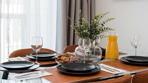 A dining table set with black plates, clear glasses, and a vase with green foliage. - Borg Loft Apt Itäpuisto (Pori)