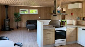 A modern kitchen with a built-in stove, wooden cabinets, and a large window. - 5 Star Holiday Home in Ebeltoft (Ebeltoft)