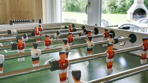 Ein Kicker mit Spielfiguren in roten und weißen Trikots, auf einem grünen Spielfeld mit weißen Linien.