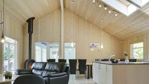 Ein modernes Interieur mit Holzboden, einem schwarzen Ledersofa, einer Küchenzeile und einem Esstisch.