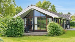 Una casa moderna con ampie vetrate, un patio coperto e un giardino curato.