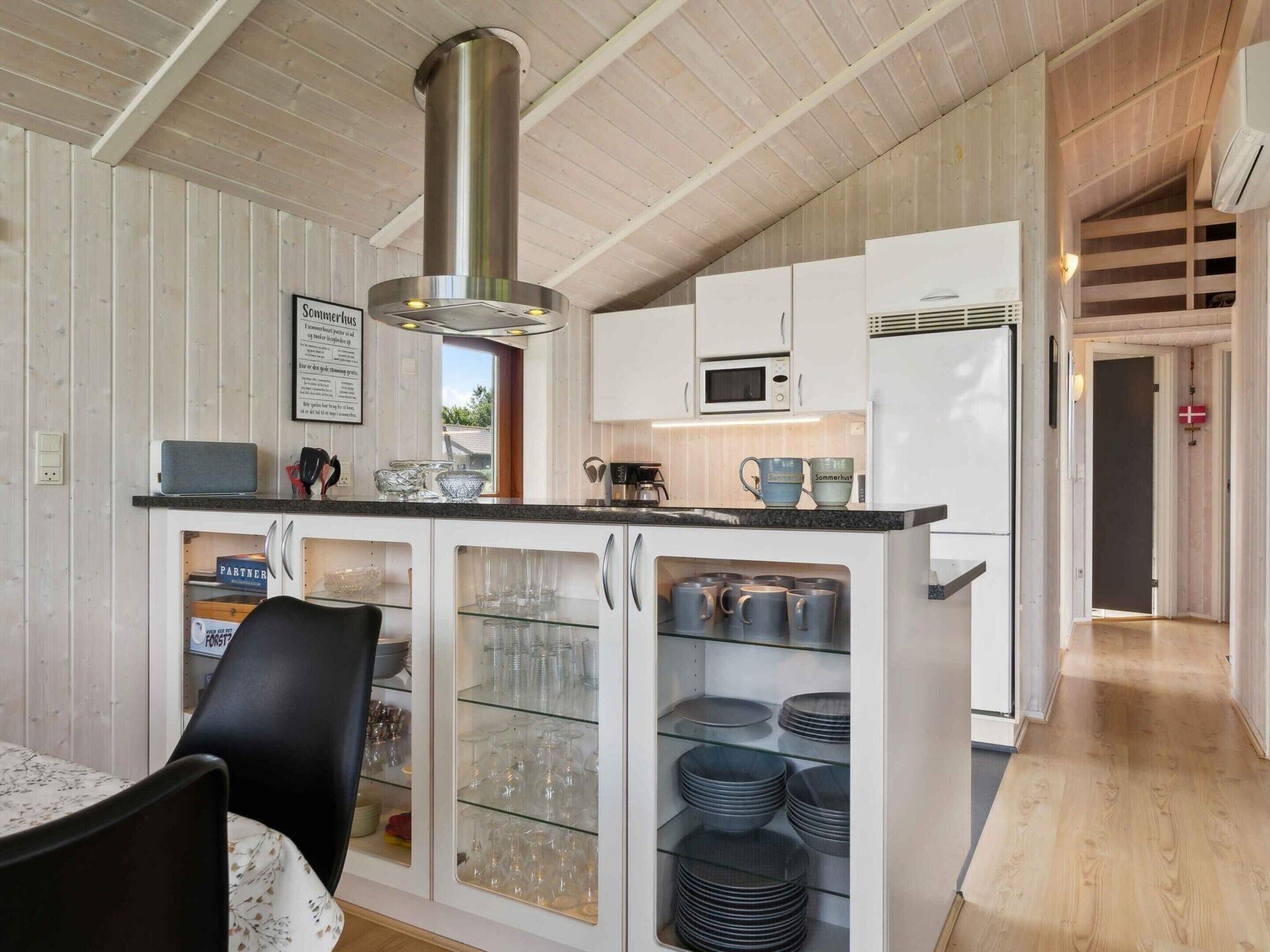 A modern kitchen with white cabinetry, a stainless steel range hood, and a built-in microwave.