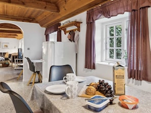 A dining area with a table set for two, a refrigerator, and a window with curtains. - 5 Star Holiday Home in Romo (Rømø)