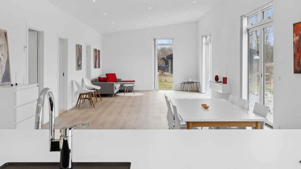 Une cuisine moderne dotée d’un îlot central, de meubles blancs et d’une grande fenêtre.